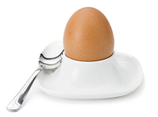 Brown boiled egg in eggcup isolated on white background.